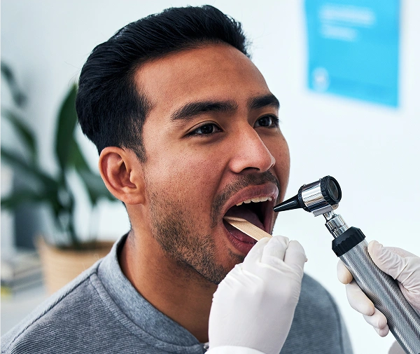 Man brushing teeth with electric toothbrush in modern dental office setting.