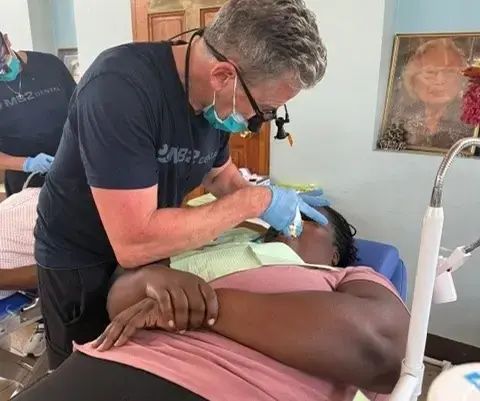 Dentist providing dental care to patient during community outreach event in New York.