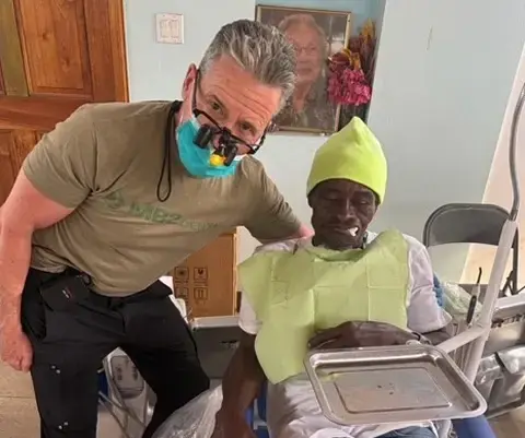 Dental volunteer assisting young patient during community health mission visit.