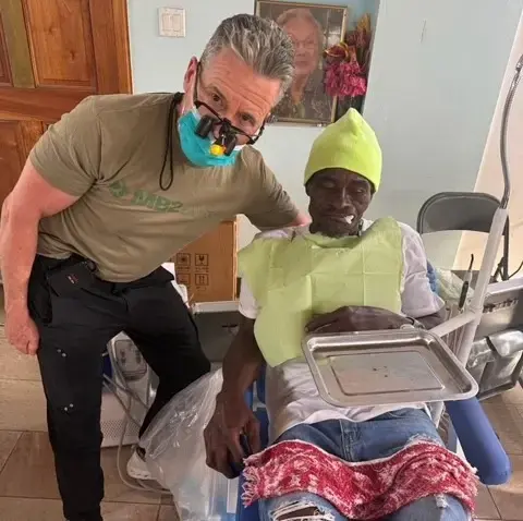 Dentist examining patient during community dental outreach event in New York.