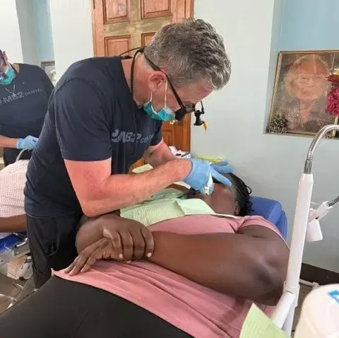 Dentist providing dental treatment to patient at community clinic in New York.